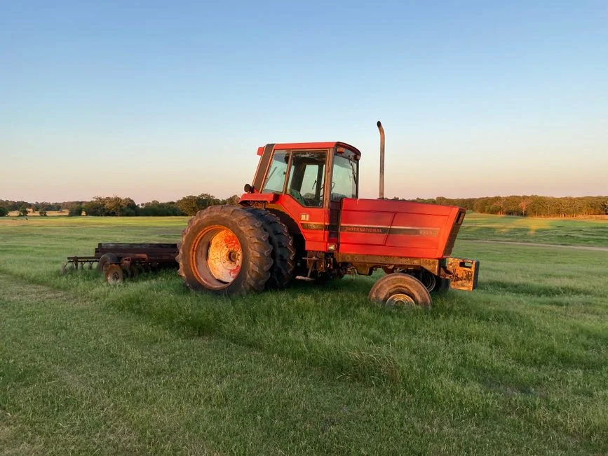 Red tractor with large rear tires parked in a green field