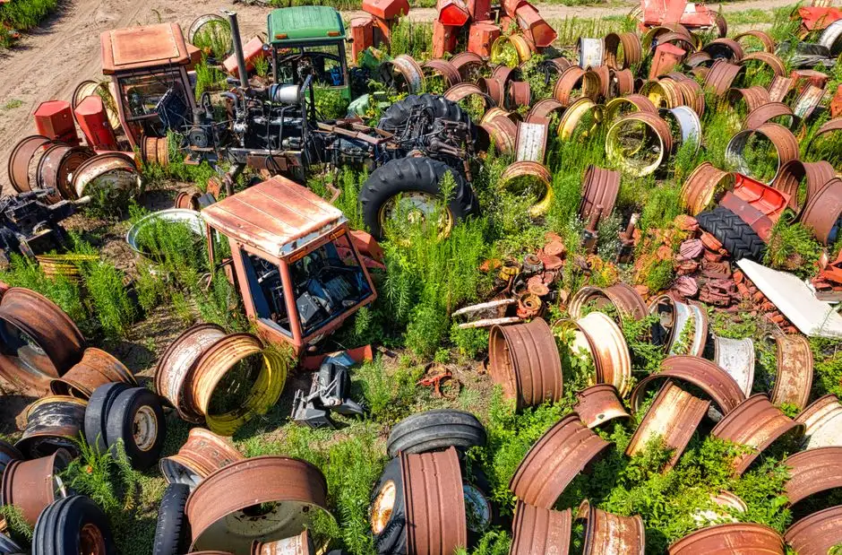 Rusty used tractor parts and wheels lying in a grassy yard