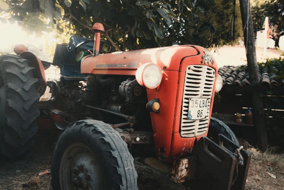 Tractor Tire Types Explained: R1 vs R2 vs R3 vs R4 A classic red tractor parked in an outdoor rural farm environment, bathed in warm sunlight