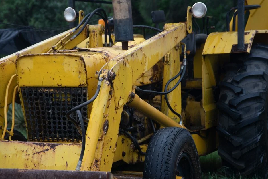 Close-up view of a weathered yellow tractor in an outdoor field setting