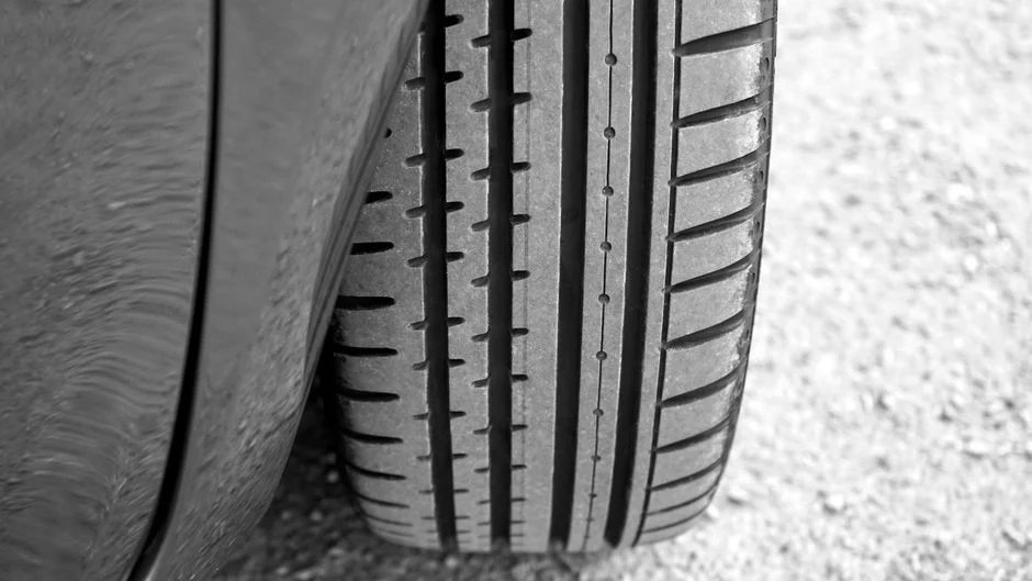Detailed view of vehicle tire on a gravel surface, showcasing tread pattern