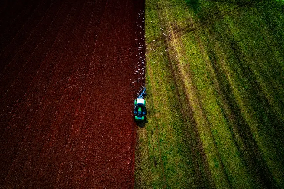 Drone captures tractor farming in Otterton, England, contrasting green and brown fields