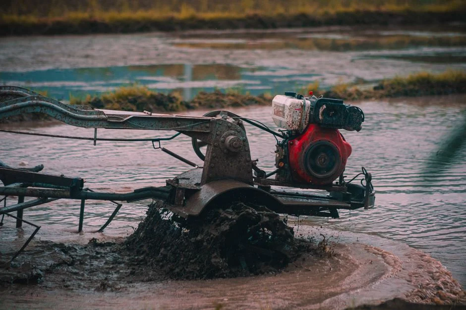 Close-up of a tractor plowing through waterlogged farmland, preparing for cultivation