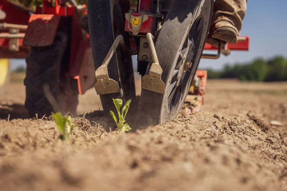 Tractor Tire Types Explained: R1 vs R2 vs R3 vs R4 Tractor in field preparing soil for planting vegetables, close-up view with selective focus