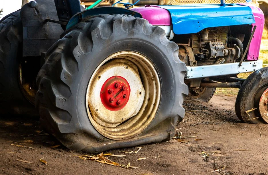 Vibrant tractor with a flat tire showcasing rural farming equipment in an outdoor setting