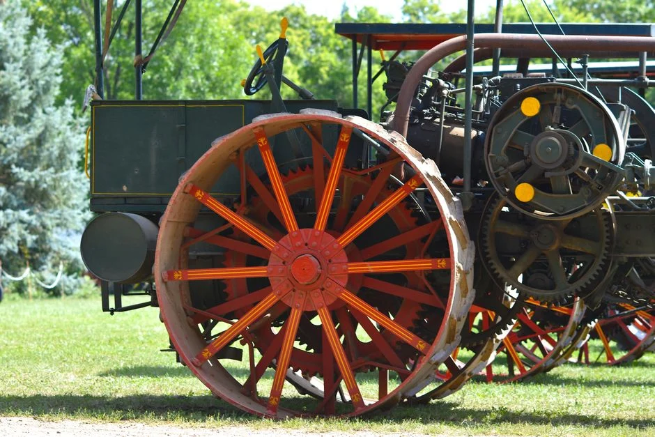 Close-up of a vintage red tractor wheel with intricate design in a sunny farm environment