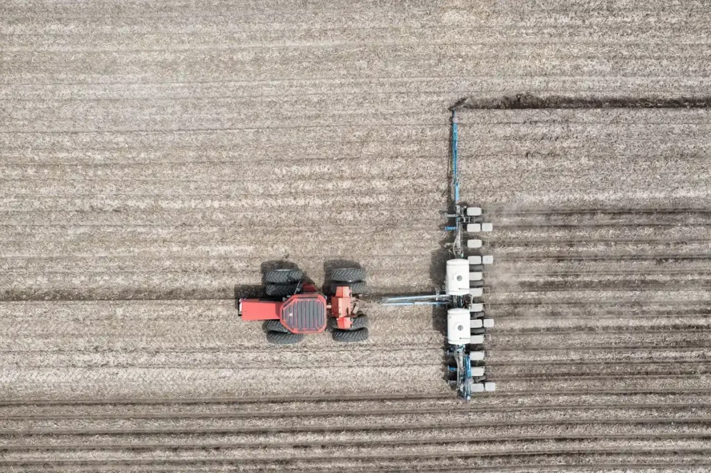Aerial shot of a tractor plowing farmland in Minnesota, showcasing efficient agricultural machinery.