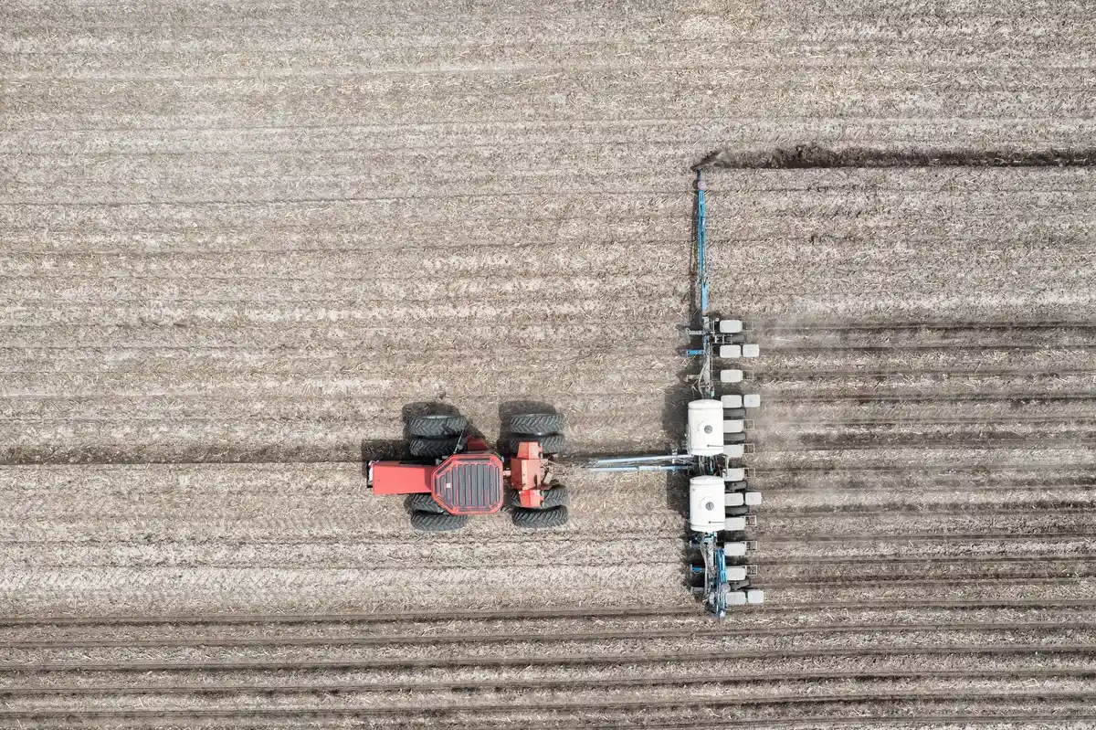 Aerial shot of a tractor plowing farmland in Minnesota, showcasing efficient agricultural machinery.