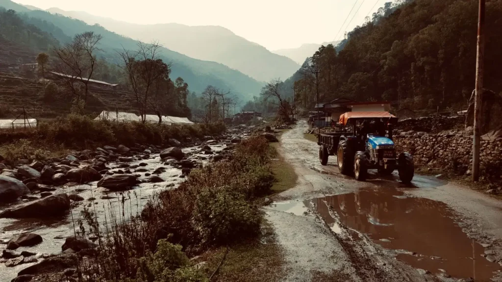 Blue tractor on a muddy rural road in autumn
