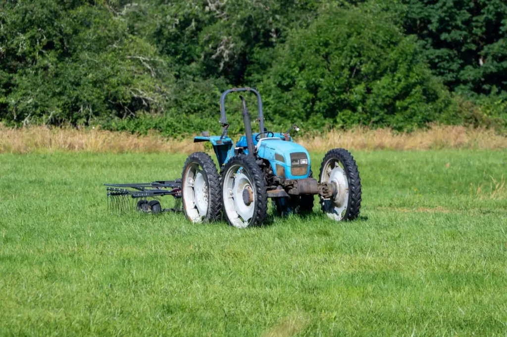 Firestone Tractor Tires: Who Makes Them and Which Line Fits Blue tractor parked in a green field with trees behind it