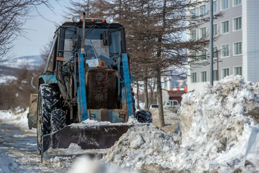 Blue tractor plowing snow on a winter road