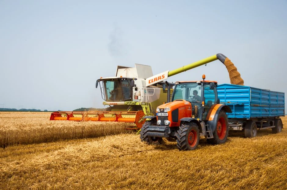 A tractor and combine harvester working in a wheat field