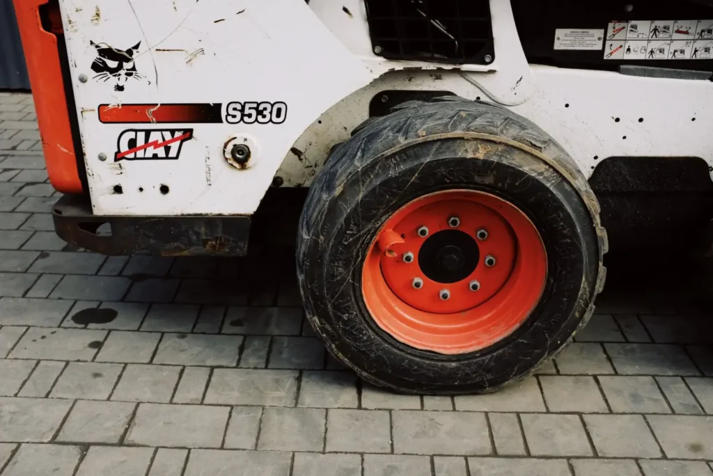 Dirty wheel of a small loader parked on pavement