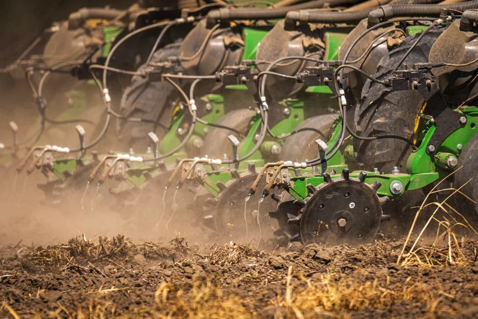 Close-up of farm machinery wheels sowing seeds on a dusty field