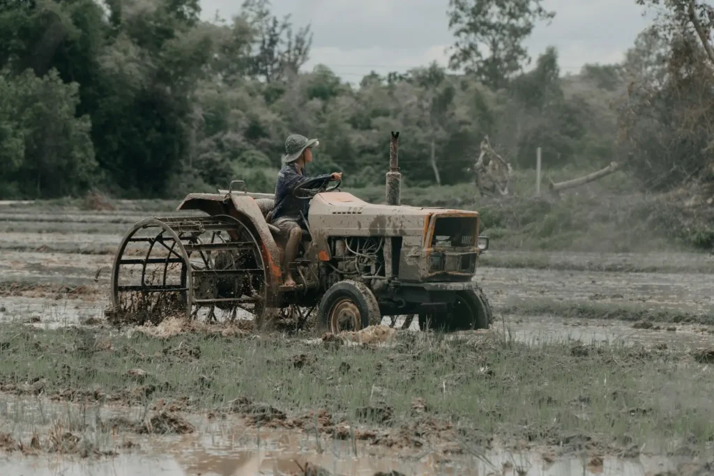 Farmer driving a tractor through a muddy field