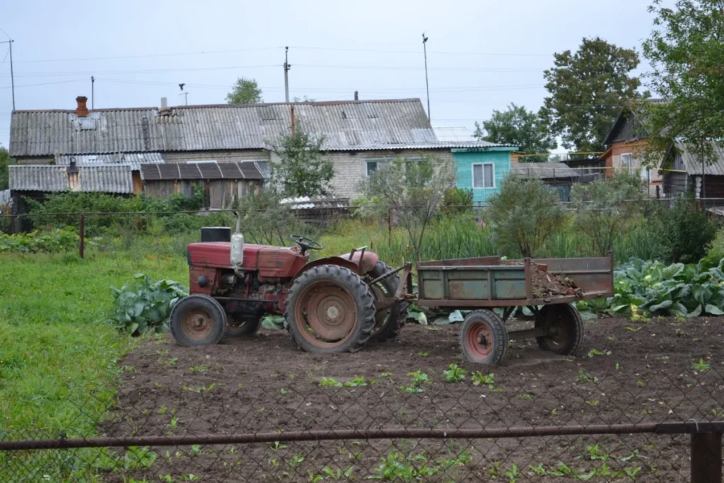 Vintage tractor parked in a rural backyard beside green vegetation