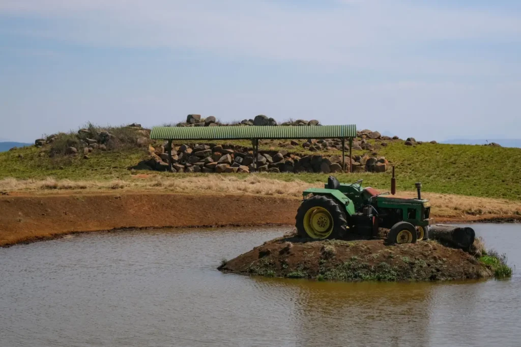 Green tractor parked on a small islet surrounded by a pond in the countryside