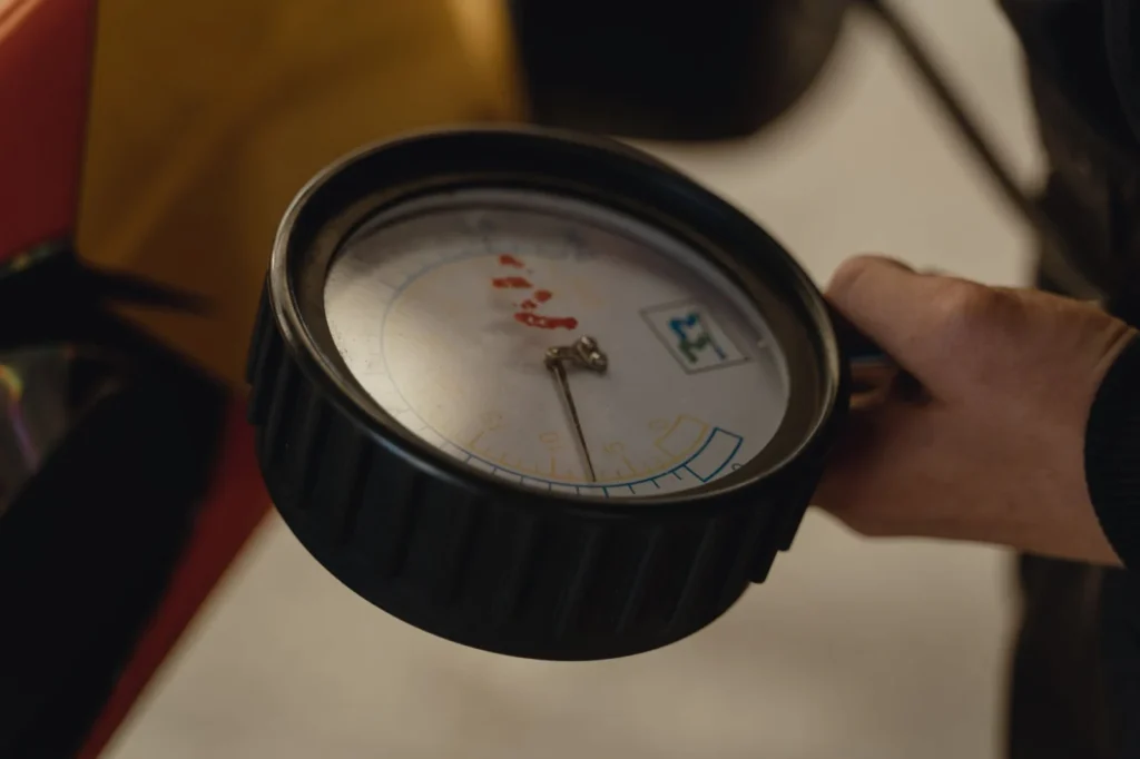 Tires for Compact Tractors: R1, R3 or R4 Tread? Hand holding a pressure gauge in a close-up