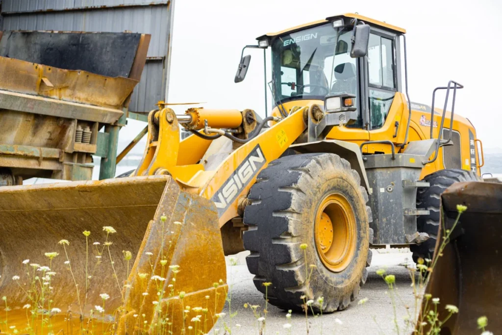 Close-up of an industrial loader with a large wheel and tire on a worksite