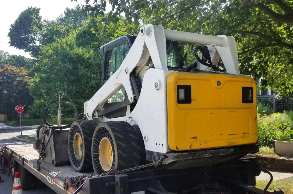 White skid steer loader parked on a trailer