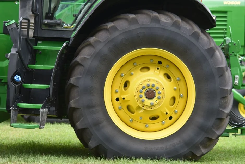Big Tractor Tires: How Big They Get, What They Fit and Cost Close-up of a yellow wheel on a green tractor, showcasing agricultural equipment details