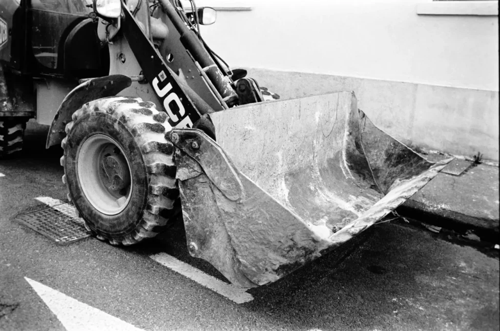 Black and white close-up of a construction loader bucket on a street