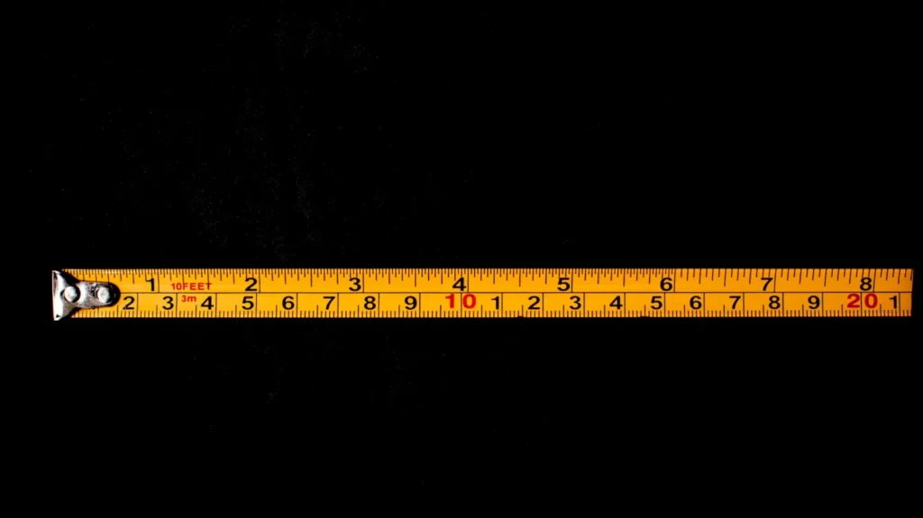 Yellow tape measure unrolled across a black surface