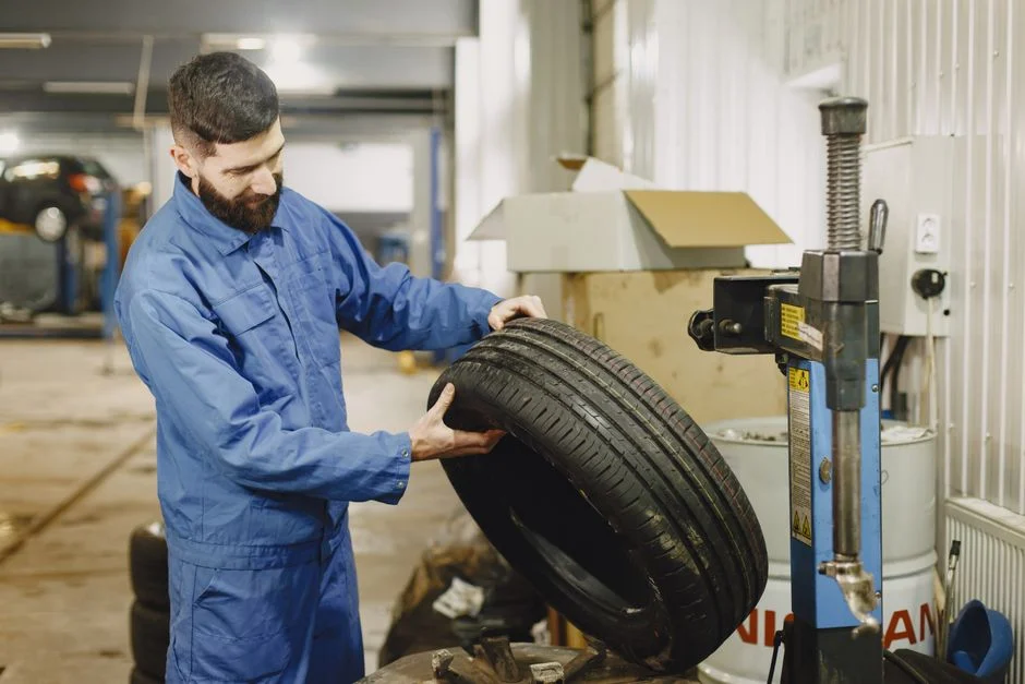 Mechanic in blue uniform examining a tire in an automotive garage