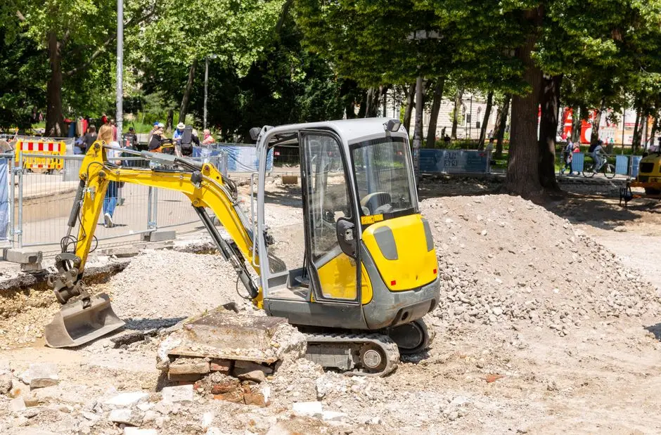 Yellow mini excavator working on a city construction site