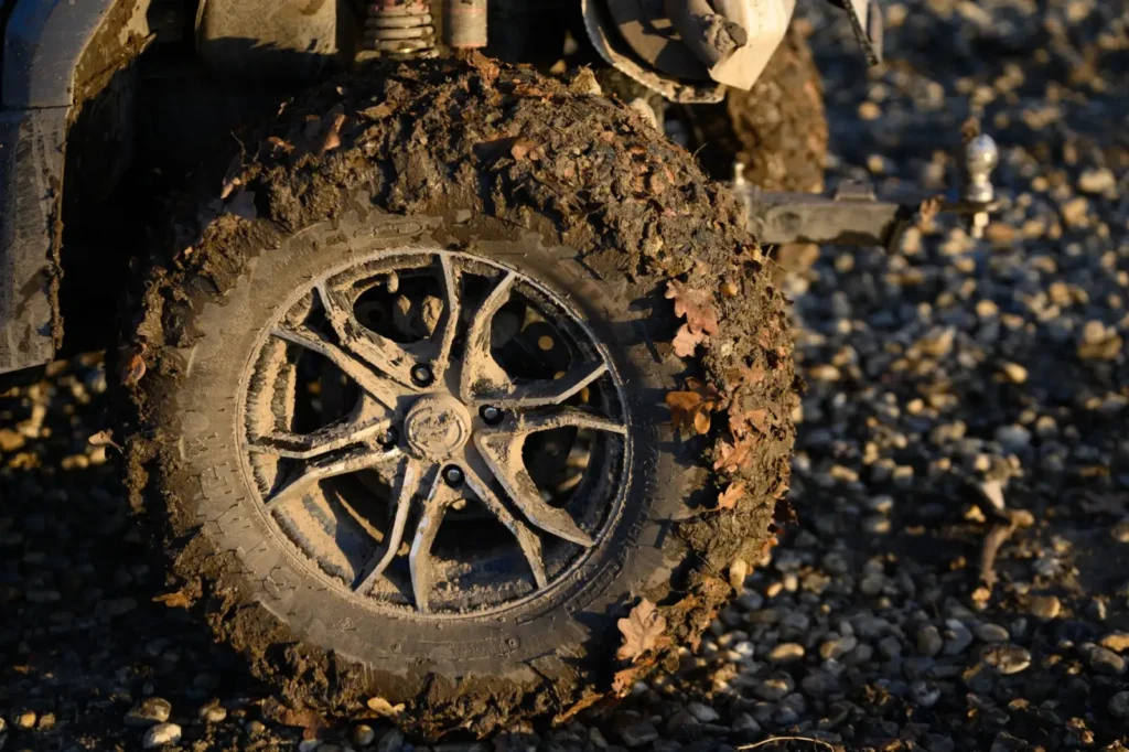 Close-up of a mud-covered tire with leaves stuck in the tread