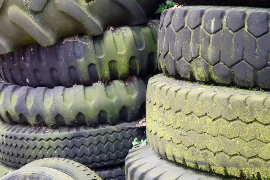 DOT Tractor Tires: How to Read the Date Code and Tire Age Old moss-covered tires stacked outdoors
