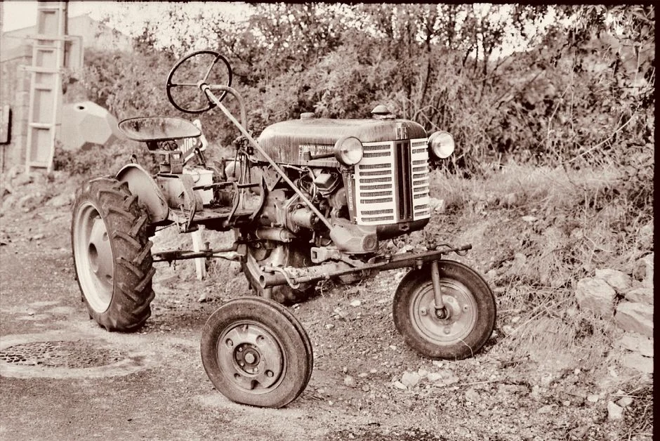 Classic sepia-toned image of an old tractor in a rural landscape