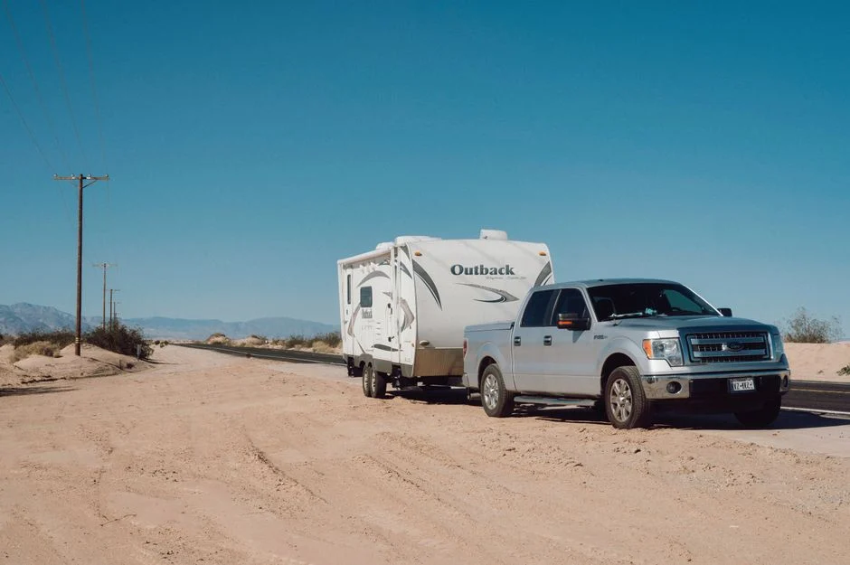 Silver pickup truck towing a travel trailer on a desert road
