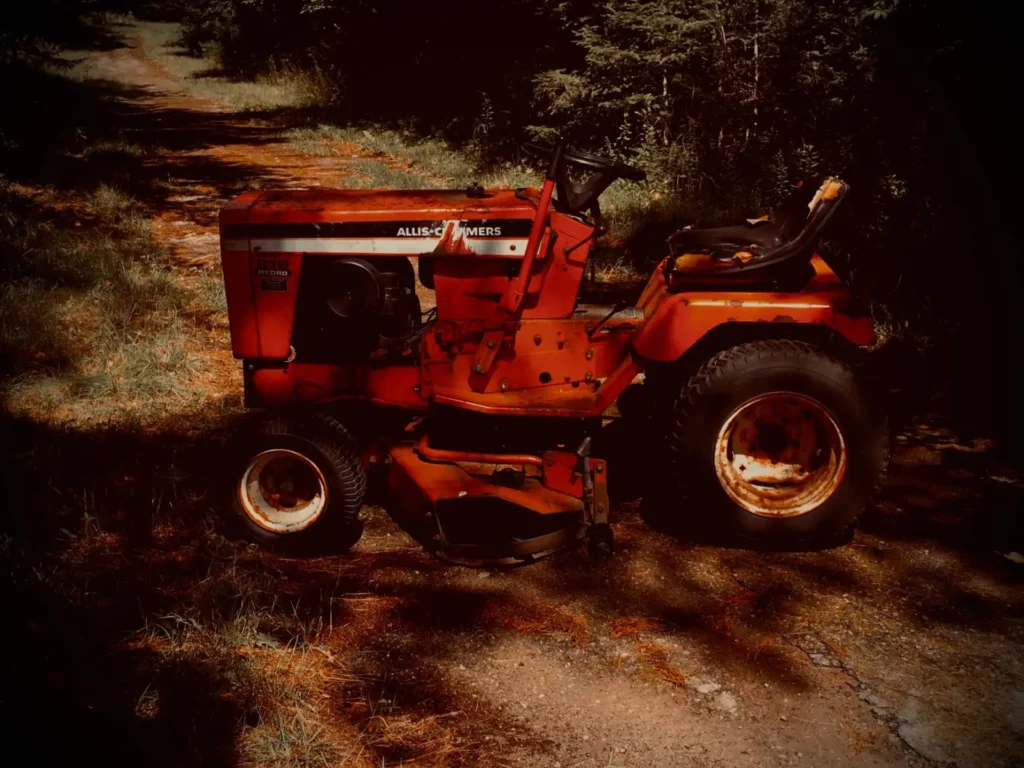 Tires for Compact Tractors: R1, R3 or R4 Tread? Classic red lawn tractor parked on a dirt road with trees behind it