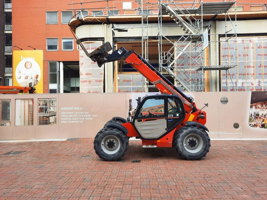 Red telehandler parked at a construction site beside scaffolding