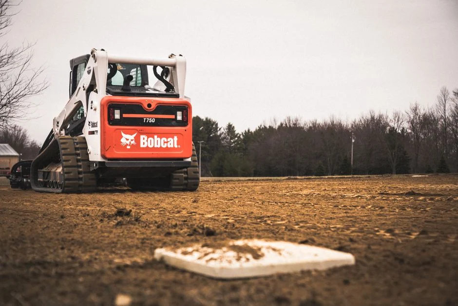 Skid loader grading a baseball field under construction