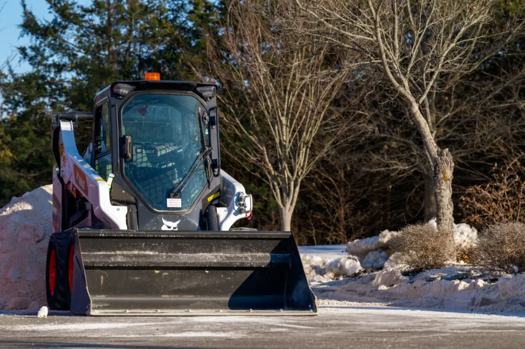 Skid steer loader clearing snow on a winter day