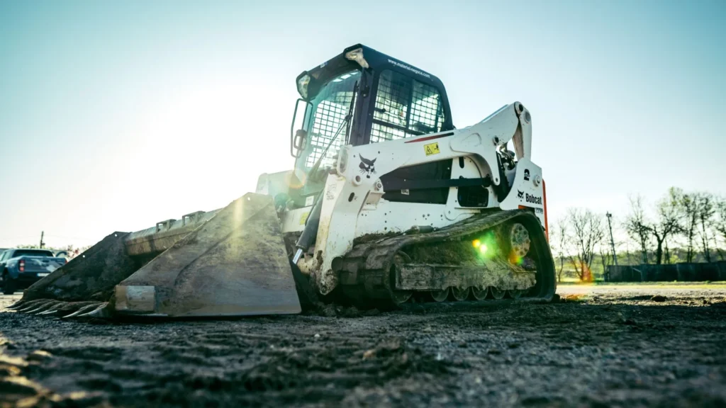 Skid steer loader working on a construction site in bright sunlight