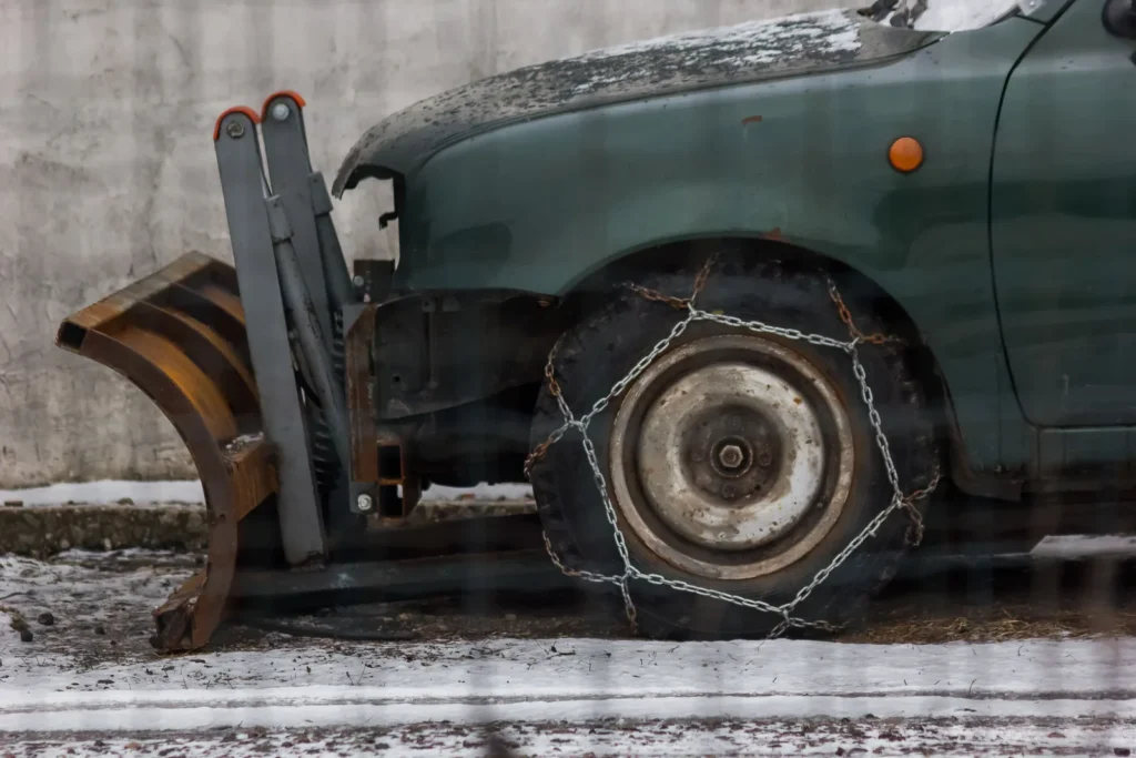 Close-up of a snowplow vehicle with chains on its tires