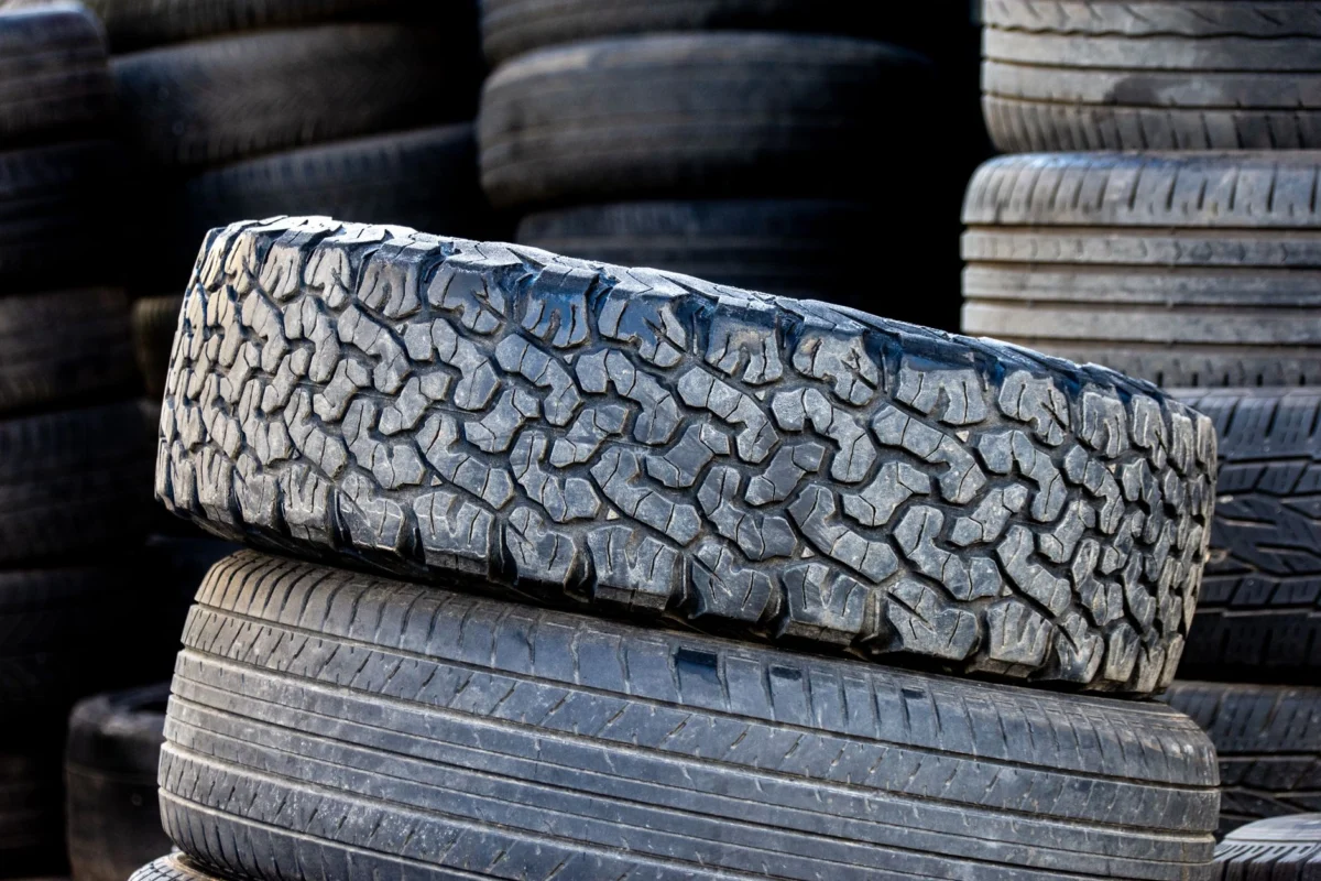Rear Tractor Tires: Sizes, Tread and How to Pick a Pair Close-up of stacked automotive tires showcasing rugged tread patterns in an outdoor setting.