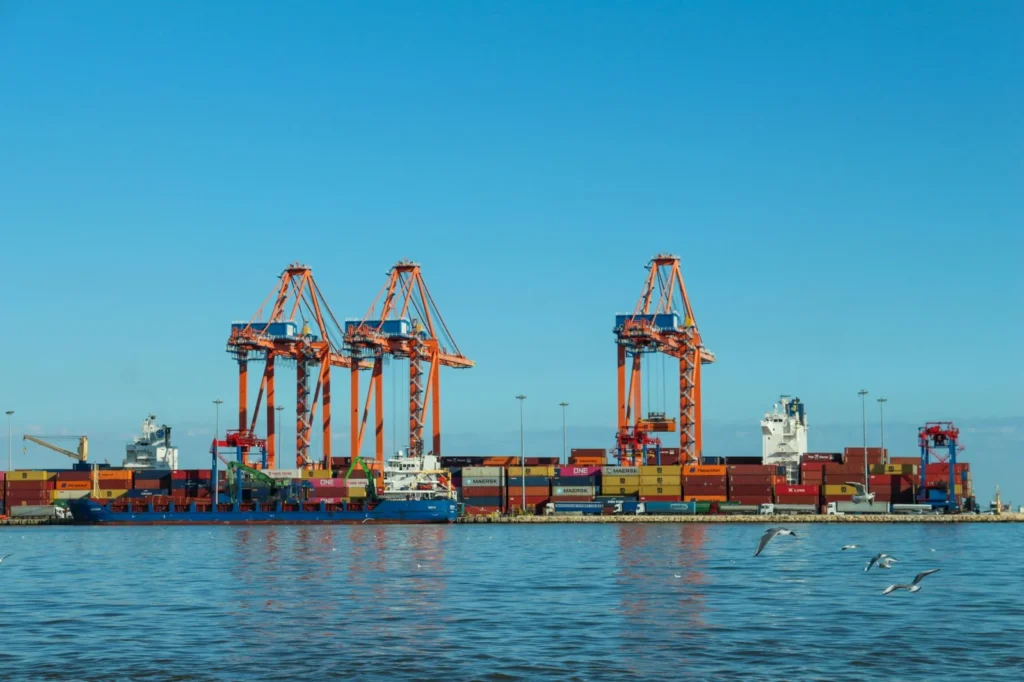 Container port with large cranes and ships against a blue sky