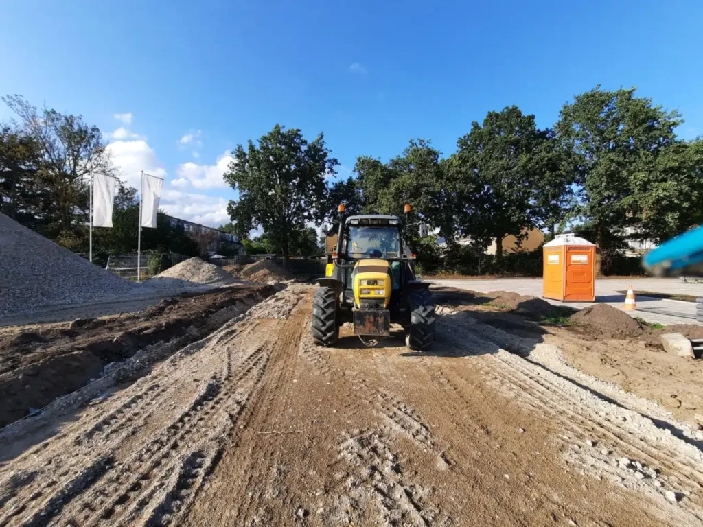 Tractor on a dirt road at a construction site under a blue sky