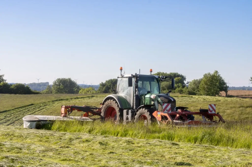 Tires for Compact Tractors: R1, R3 or R4 Tread? Tractor mowing a lush green field on a sunny day