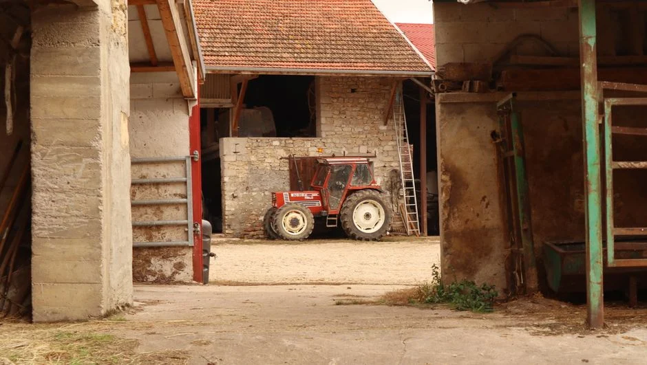 Big Tractor Tires: How Big They Get, What They Fit and Cost A vintage tractor parked inside a barn in a rustic farm setting