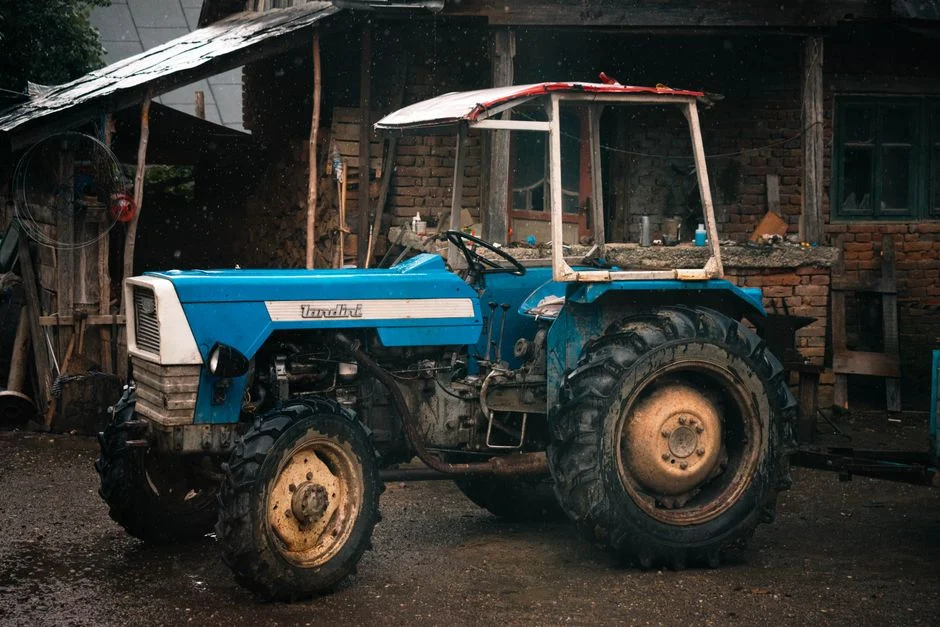 Blue tractor parked on a rural farm in Măgoaja, Romania during a rainy day
