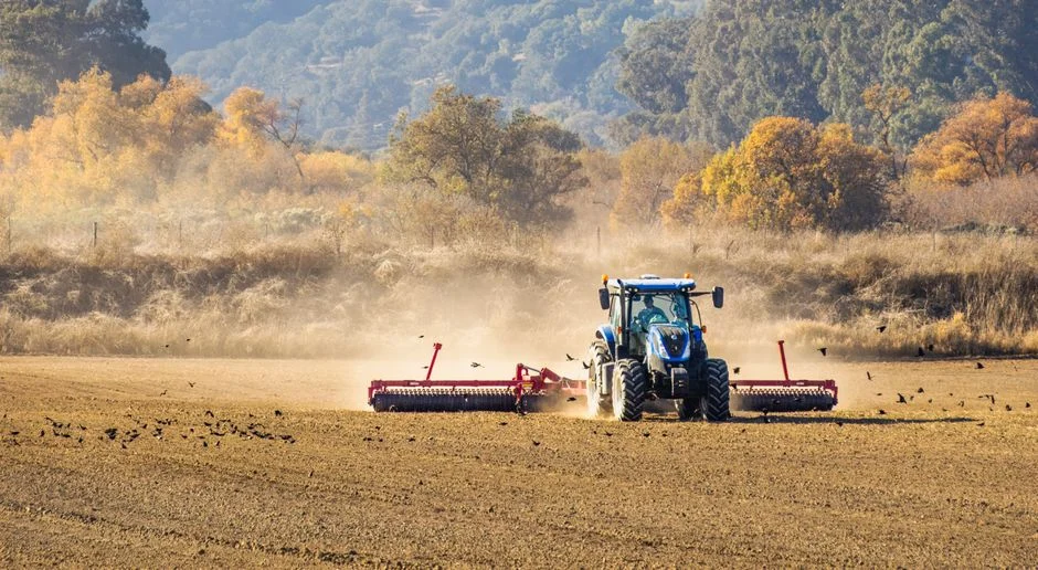 Tractor on large rear wheels plowing a field in autumn