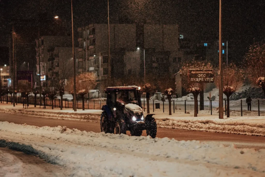 A lone tractor plowing a snow-covered street at night