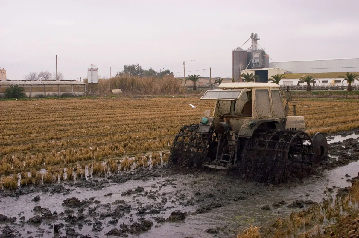 Rear Tractor Tires: Sizes, Tread and How to Pick a Pair A tractor moves through a muddy, flooded farm field, showcasing agricultural challenges.