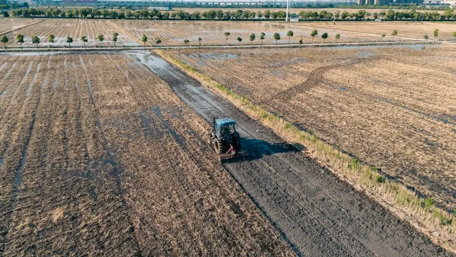 Big Tractor Tires: How Big They Get, What They Fit and Cost Aerial shot of a tractor plowing a wet field in Hangzhou, Zhejiang, China