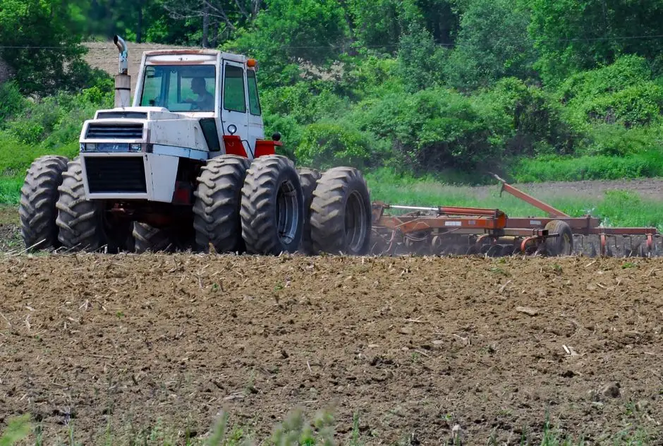 Big Tractor Tires: How Big They Get, What They Fit and Cost A tractor with dual wheels tills a field, preparing it for planting during summer